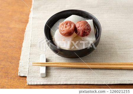 盛在黑色碗中的梅花、筷子和餐墊 126021255