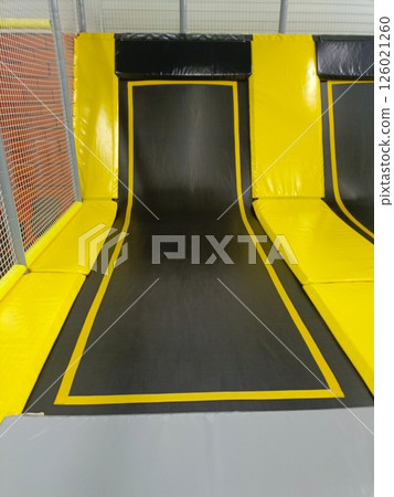 Close-Up of Indoor Trampoline with Safety Padding in Brightly Lit Play Area 126021260