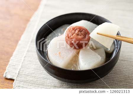 Ume Nagashi served in a black bowl, radish held with chopsticks 126021313
