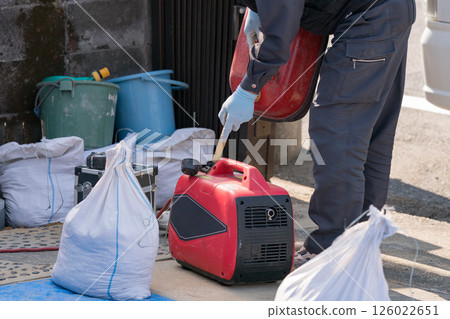Construction worker refueling a generator with gasoline 126022651