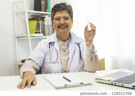 Woman doctor taking notes on clipboard while sitting at her table in office Woman doctor taking notes on clipboard while sitting at her table in office 126022706