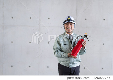 A middle-aged man holding a fire extinguisher and calling for safety measures 126022763