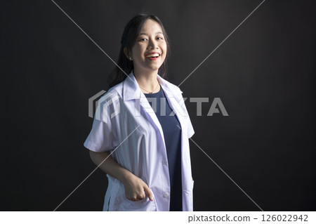 Young Asian female physician, Med student or resident doctors wear face mask standing on black background. 126022942