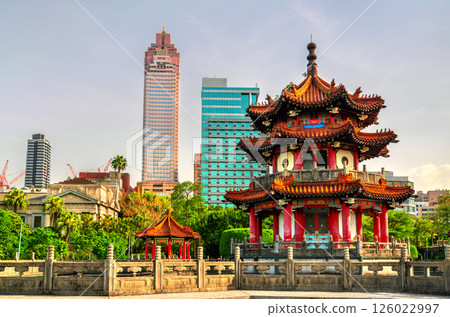 A traditional Chinese pavilion in 228 Peace Memorial Park, Taipei, Taiwan, stands elegantly before a backdrop of modern skyscrapers, reflecting the contrast between cultural heritage and urban 126022997