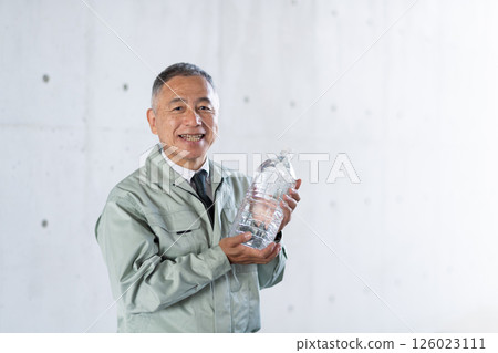 A veteran male employee holds drinking water stockpiled for disasters 126023111