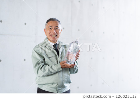 A veteran male employee holds drinking water stockpiled for disasters 126023112