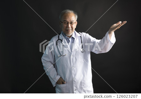 Asian doctor with stethoscope around his neck with thumb up hand stand on black background. 126023207