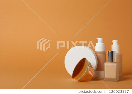 Bottles of foundation and cosmetic brush on orange background, space for text 126023527
