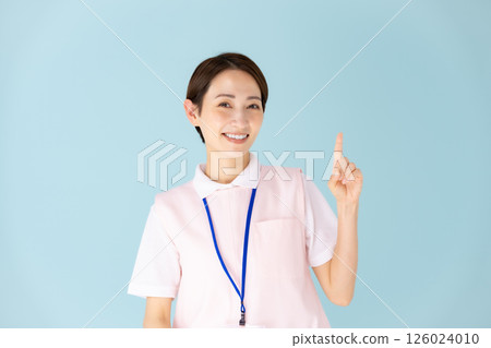 Woman in apron, caregiver, nursery teacher, medical, pointing Woman in apron, caregiver, nursery teacher, medical, pointing 126024010