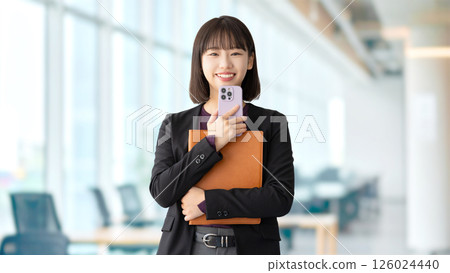 Smiling woman/businesswoman holding a computer and smartphone 126024440