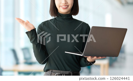 A smiling woman/businesswoman giving directions while holding a computer A smiling woman/businesswoman giving directions while holding a computer 126024441