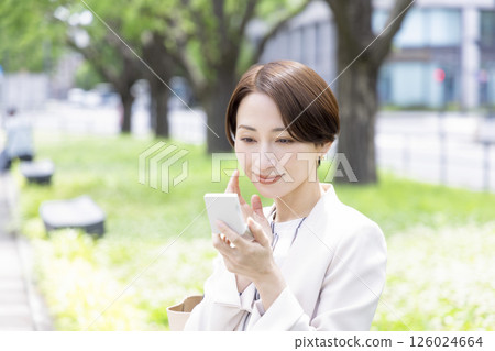 Business woman sitting on a bench and touching up her makeup 126024664