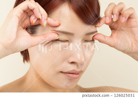 A woman lifts her eyebrows upwards. 126025031