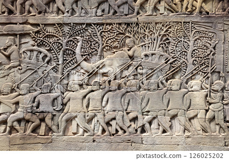 Wall carving with depicting troops, soldiers, military leaders on elephants in Prasat Bayon Temple, Angkor Wat complex, Siem Reap, Cambodia. Bas-relief - King of Angkor Jayavarman VII with his army Wall carving with depicting troops, soldiers, military leaders on elephants in Prasat Bayon Temple, Angkor Wat complex, Siem Reap, Cambodia. Bas-relief - King of Angkor Jayavarman VII with his army 126025202