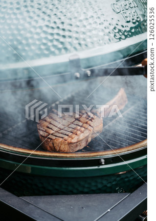 Grilling juicy Tomahawk steak on barbecue grill with smoke rising. 126025536