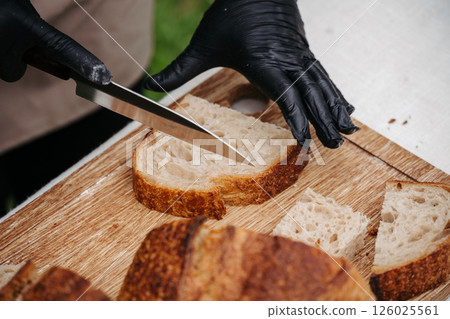 Cook cutting rustic sourdough bread on cutting board. Cook cutting rustic sourdough bread on cutting board. 126025561