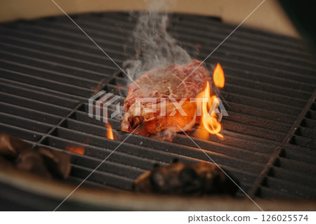 Grilling New York Strip steak over open flame on barbecue grill. Grilling New York Strip steak over open flame on barbecue grill. 126025574