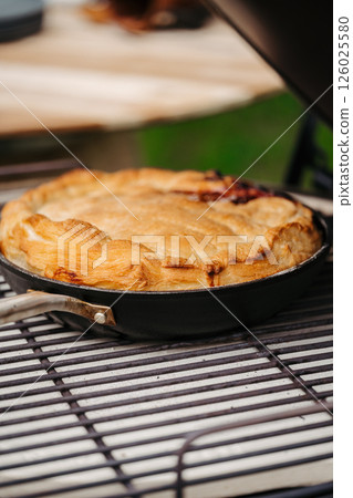 Homemade apple pie baked in a skillet on an outdoor grill 126025580