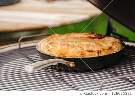 Homemade apple pie baked in a skillet on an outdoor grill 126025581