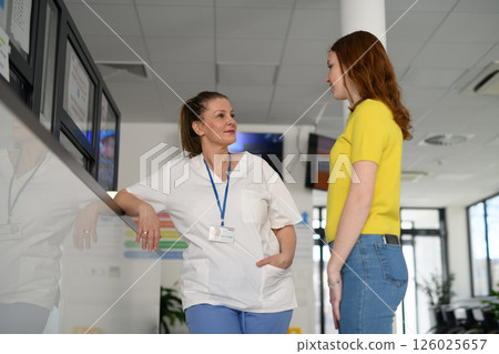 Nurse talking with teenage patient in hospital waiting room. Nurse talking with teenage patient in hospital waiting room. 126025657