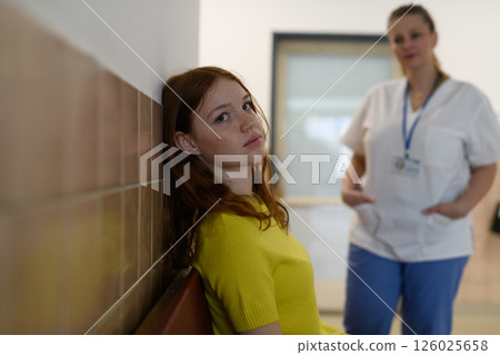Teenage girl waiting alone in hospital waiting area before medical checkup. Teenage girl waiting alone in hospital waiting area before medical checkup. 126025658