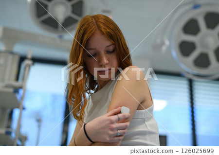 Teenage girl with diabetes checking CGM sensor during hospital visit. 126025699