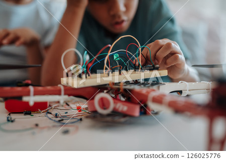 Young schoolboy assembling robotic kit, working with circuit board at home. 126025776