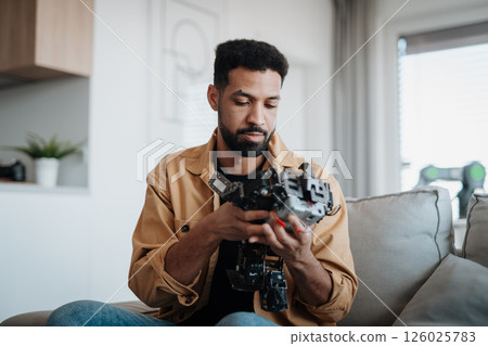Handsome engineer student working on robot project at home. 126025783