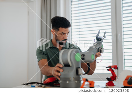 Young engineer building and programming a robotic arm at home. Young engineer building and programming a robotic arm at home. 126025808