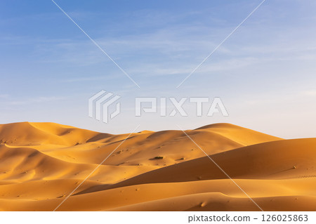 Lowering horizon of sand dunes with prevailing blue sky with clouds. Lowering horizon of sand dunes with prevailing blue sky with clouds. 126025863