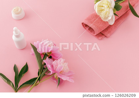 Towel with body care products and peony flowers on the pink background. 126026209