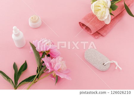 Towel with body care products and peony flowers on the pink background. Towel with body care products and peony flowers on the pink background. 126026210