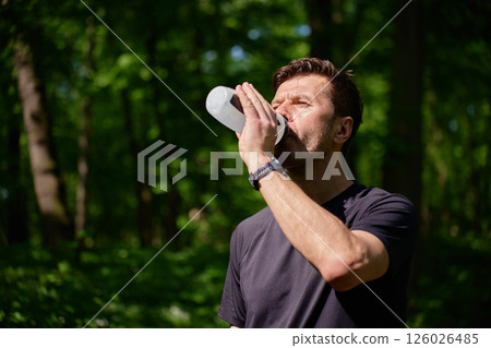 Man drinking water after outdoor run in forest 126026485