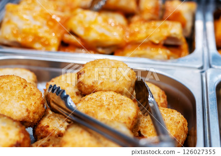 A detailed close up view of a tray filled with various foods and tongs 126027355