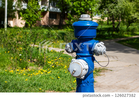 A bright blue fire hydrant is prominently sitting beside the road 126027382