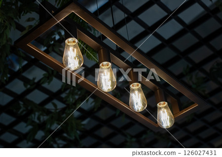 Four light bulbs are elegantly hanging down from a wooden frame 126027431