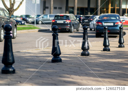 There is a striking row of black chess pieces displayed on the sidewalk There is a striking row of black chess pieces displayed on the sidewalk 126027510