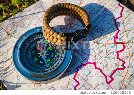 magnetic compass on detailed paper map, essential navigation tool for hiking and outdoor exploration magnetic compass on detailed paper map, essential navigation tool for hiking and outdoor exploration 126028166
