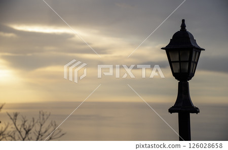 Garden lamp on a pillar. Beautiful bright lamp on a background of sunset 126028658