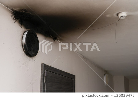 Burnt out LED lamp. A lampshade lamp on the wall after a fire. Spontaneous combustion and fire in a residential building. Burnt out LED lamp. A lampshade lamp on the wall after a fire. Spontaneous combustion and fire in a residential building. 126029475