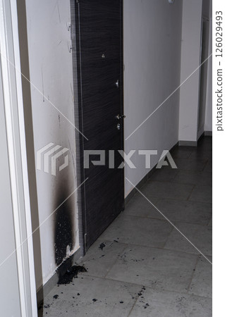 Arson of the front door of the apartment. Consequences of the fire. Black soot on the wall. 126029493