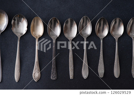 Set of different spoons. Silver cutlery on a black background. Spoon on the table 126029529