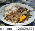Traditional Gambian Nyebbeh Meal with Rice, Black-Eyed Peas, and Scotch Bonnet Pepper on White Plate 126029834