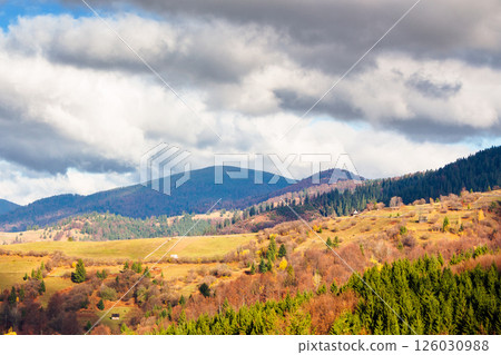 beautiful mountain countryside landscape in autumn. sky with clouds. rural scenery with forest on hill. sunny day. amazing colorful europe 126030988