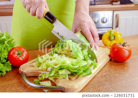 Woman chopping lettuce on cutting board... Woman chopping lettuce on cutting board... 126031731