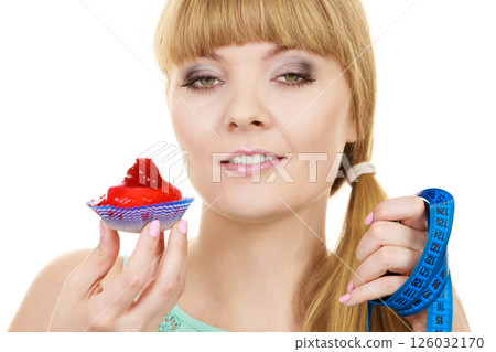 Woman holds cupcake and measuring tape. Diet 126032170