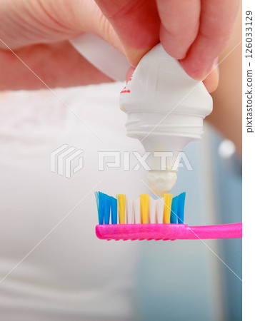 Woman hands putting toothpaste on toothbrush Woman hands putting toothpaste on toothbrush 126033129
