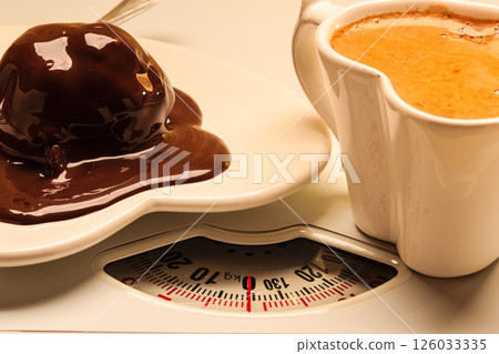 Coffee and chocolate cake on weighing scale. Coffee and chocolate cake on weighing scale. 126033335