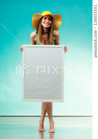 Woman in bikini holds blank presentation board. 126033501