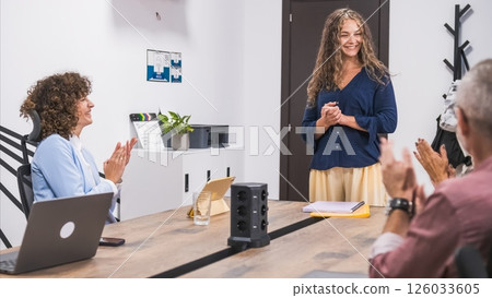 Confident happy businesswoman giving presentation to team applauding in office 126033605